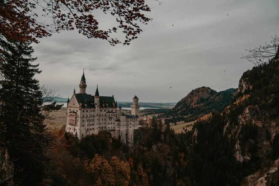 Neuschwanstein Castle surrounded by autumnal forest and mountains in Bavaria, Germany.