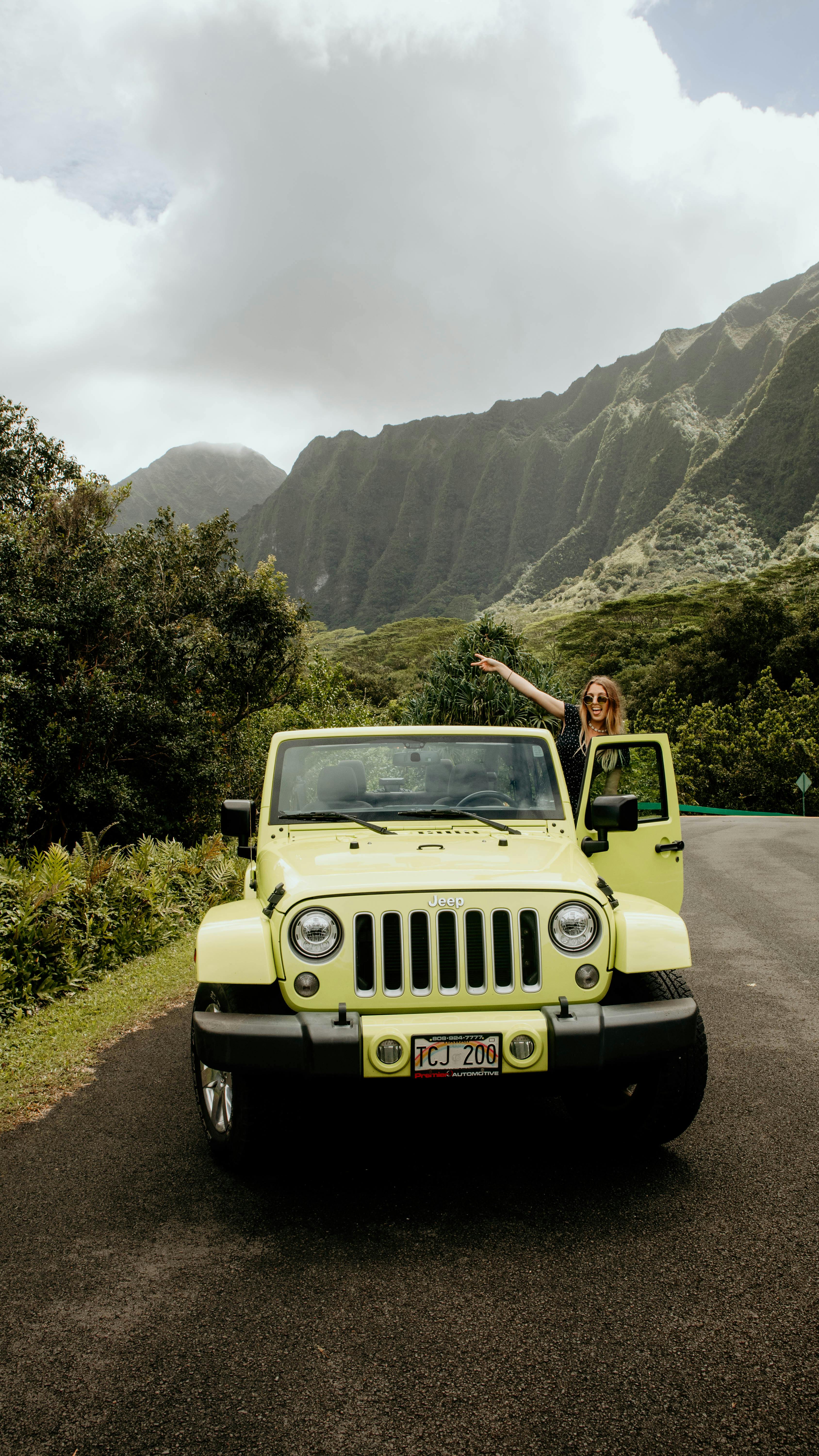 woman in yellow suv on road in mountains