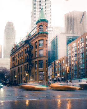 A rainy evening in Toronto with the iconic Gooderham Building in the foreground, showcasing urban life.