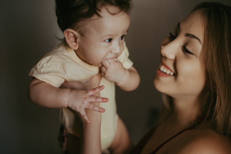 Woman Holding Her Baby In Yellow Onesie 