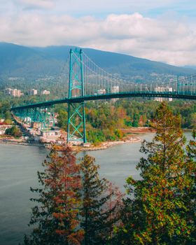 Aerial view of Lions Gate Bridge in Vancouver, showcasing lush forests and distant mountains.