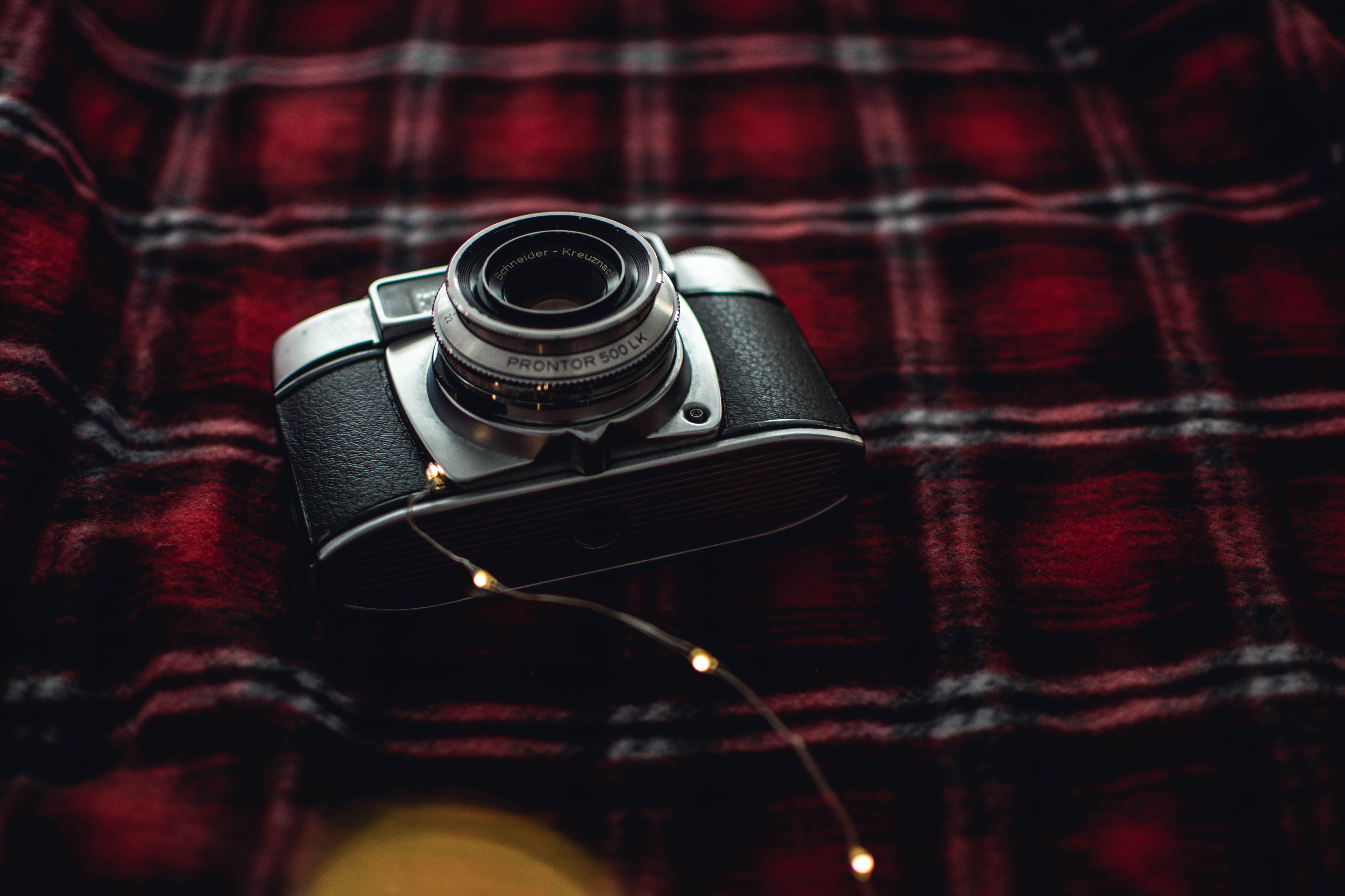 Person holding an old digital camera against a sunset, nostalgic mood