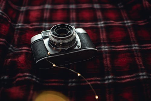 Black and Gray Point-and-shoot Camera on Red, Black, and White Plaid Textile