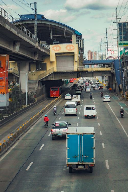 Free A bustling road scene with vehicles under an urban overpass in daylight. Stock Photo