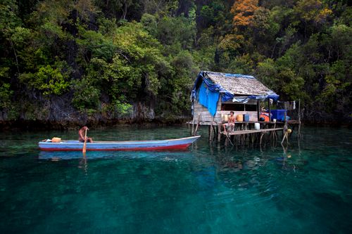 Free Serene tropical lake with a wooden house on stilts and a canoeist. Stock Photo