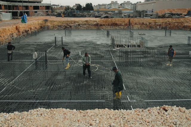 Ouvriers manipulant des armatures en acier sur un chantier de béton armé