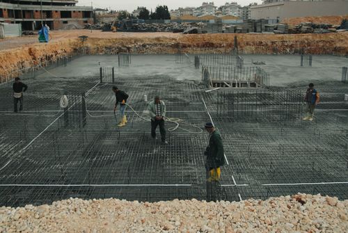 Free Industrial construction site with workers managing steel reinforcements. Stock Photo