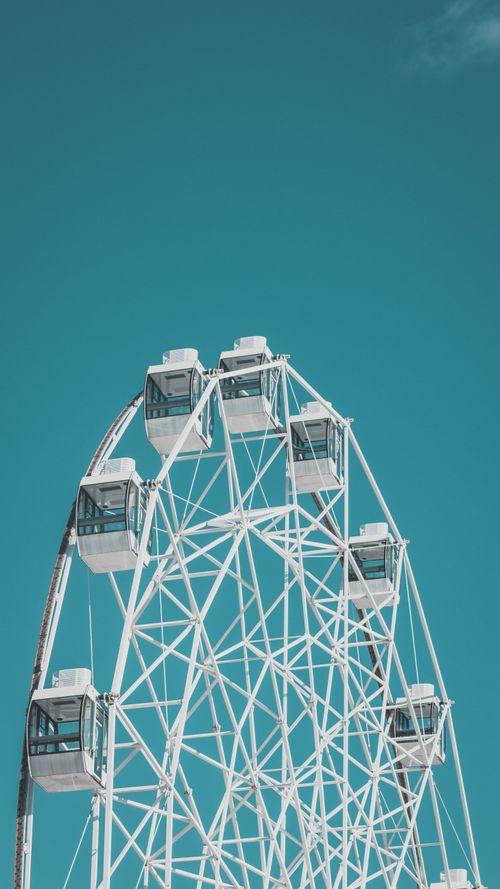 Free A close-up of a white Ferris wheel with glass pods set against a vibrant blue sky. Stock Photo