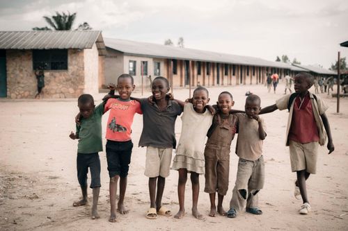 Free Group of happy children embracing each other in an African schoolyard setting. Stock Photo