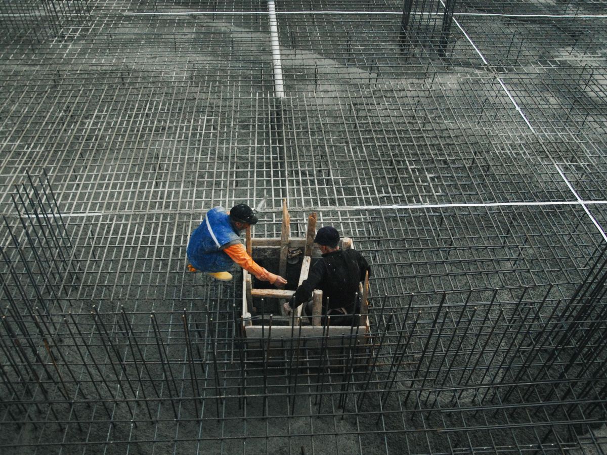 Ouvriers sur un treillis d'armature avant le coulage d'une dalle de béton