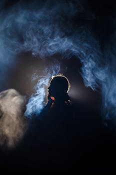 Artistic silhouette profile surrounded by ethereal smoke in dark ambiance.