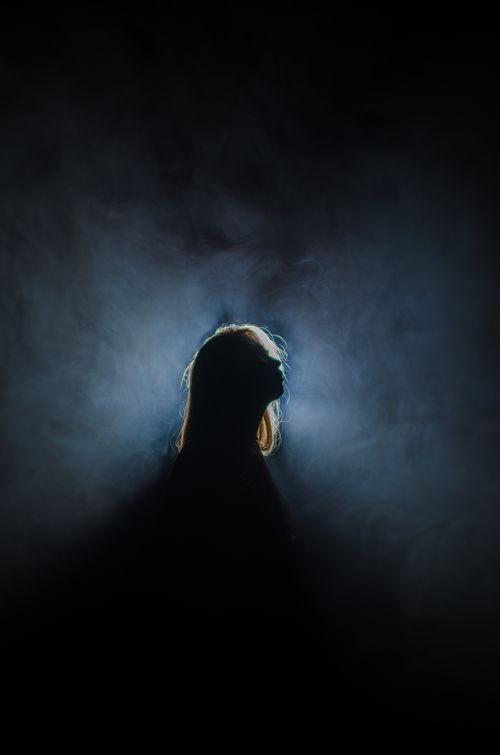 Free Ethereal silhouette of a woman in a smoky, backlit room creating a dramatic effect. Stock Photo
