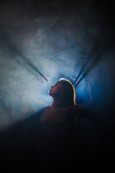 Artistic photo capturing a dancer in backlit smoke with dramatic lighting and shadows.