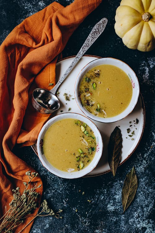 Two Pumpkin Soups Served with Herbs and Pistachio