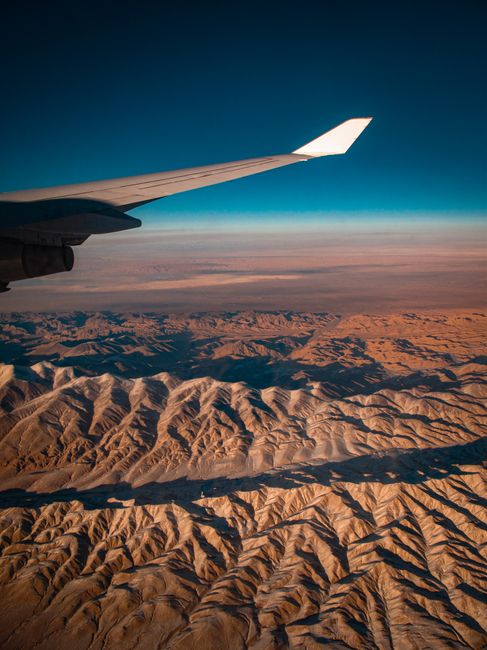 Scenic view of mountainous desert terrain from airplane window, capturing the vastness and beauty of the region.