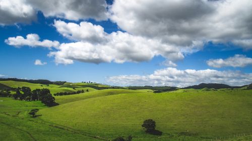 Free Beautiful green countryside with rolling hills and a vibrant blue sky with scattered clouds. Stock Photo