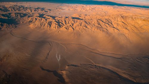 Free Stunning aerial view of expansive desert dunes and mountains at sunrise, showcasing natural beauty. Stock Photo