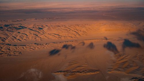 Free A breathtaking aerial shot capturing the vastness of a desert landscape with stunning evening shadows and textures. Stock Photo