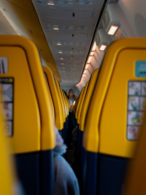 Free Explore the vibrant interior of a commercial airplane in flight, featuring bright yellow seats. Stock Photo