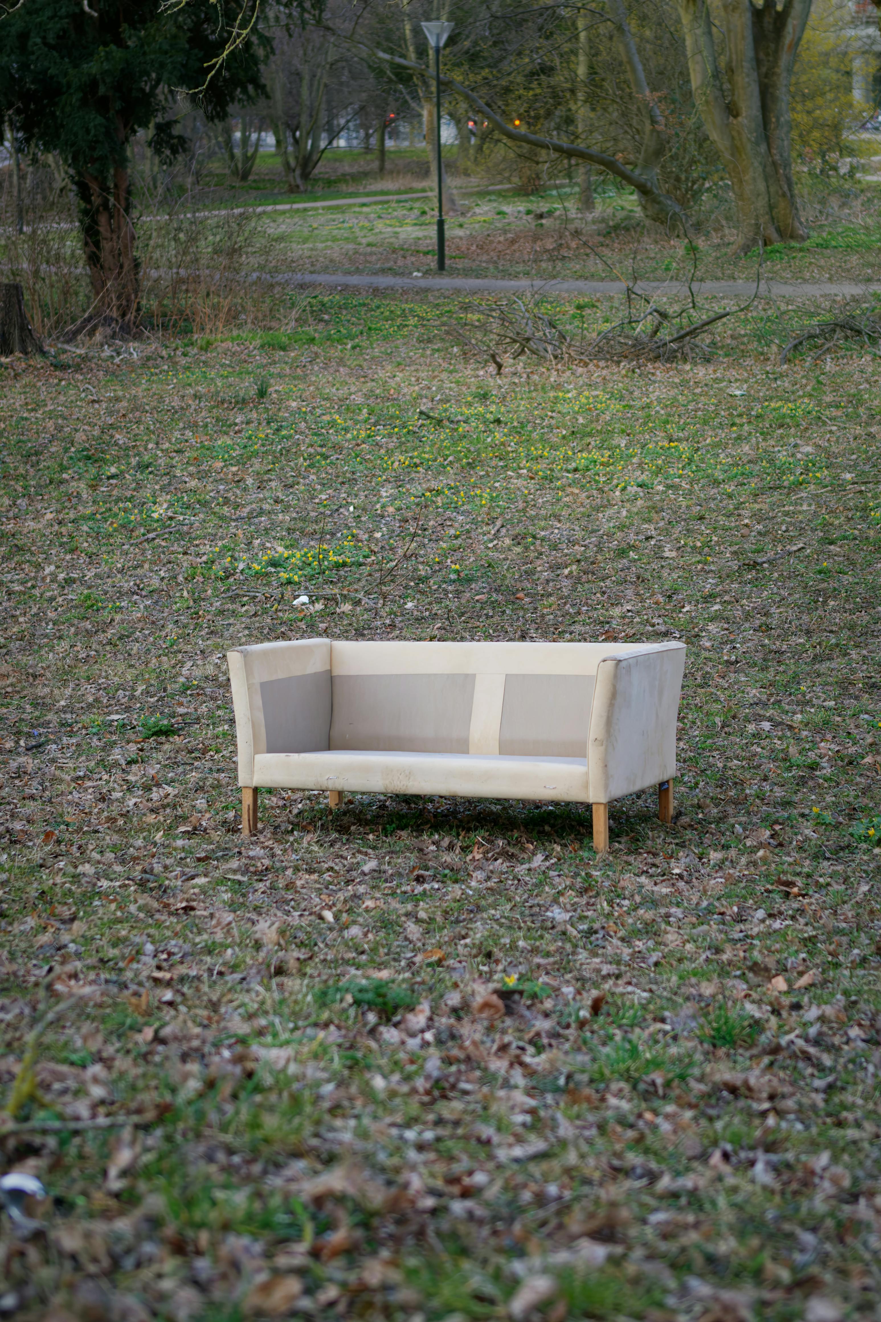 A solitary sofa sits in a leaf-covered field in Frederiksberg park, Denmark.