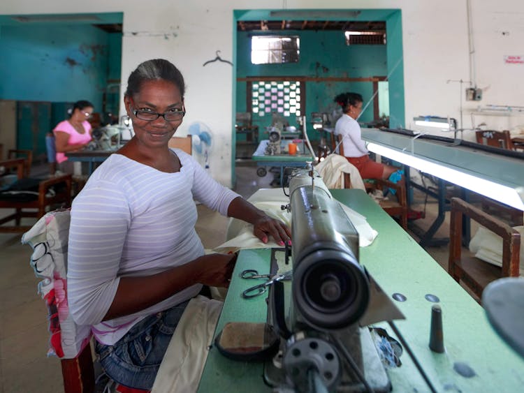 Smiling Woman Sewing In Workshop