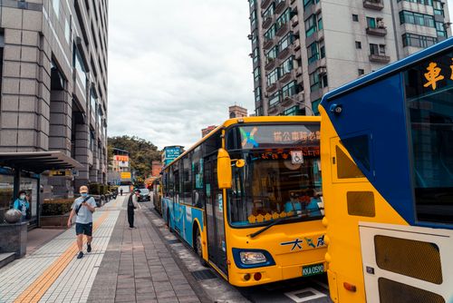 Free Urban scene with yellow city buses and pedestrians on a bustling street in Asia. Stock Photo