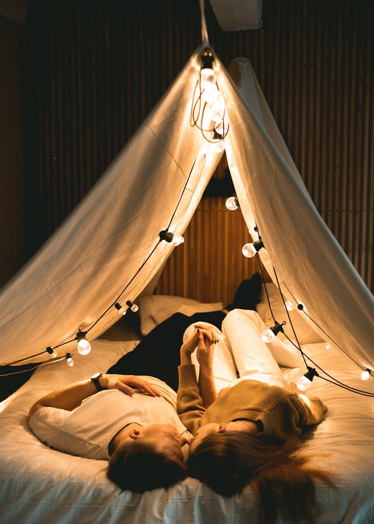 Couple Holding Hands While Lying In Bed