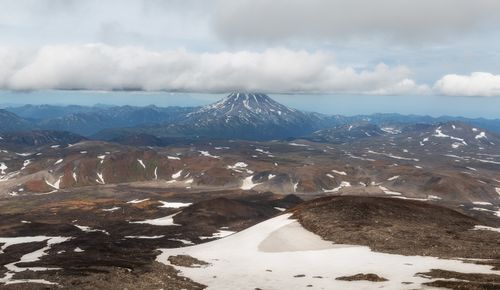 Free Stunning view of a snow-capped volcano amid rugged, scenic terrain under a cloudy sky. Stock Photo