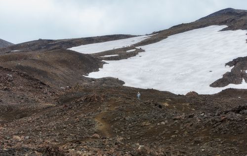 Free Hiker traversing a snowy mountain landscape, showcasing rugged terrain and winter beauty. Stock Photo