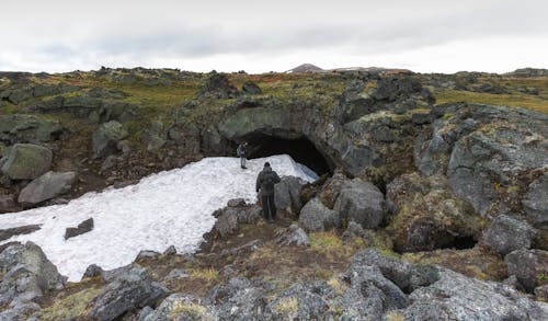 People Standing Near a Cave