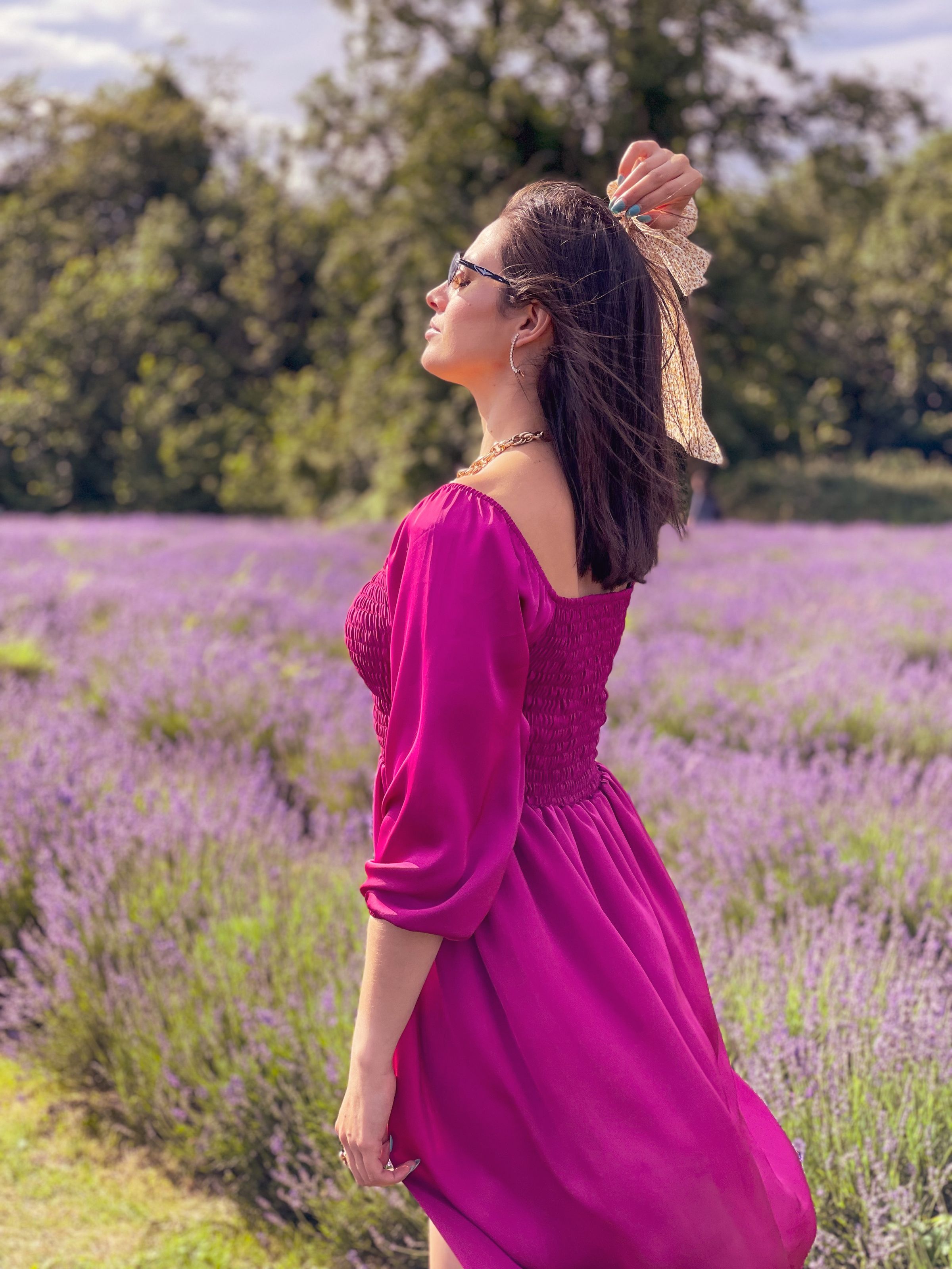 Woman in a pink summer dress walking through a flower field in hot weather