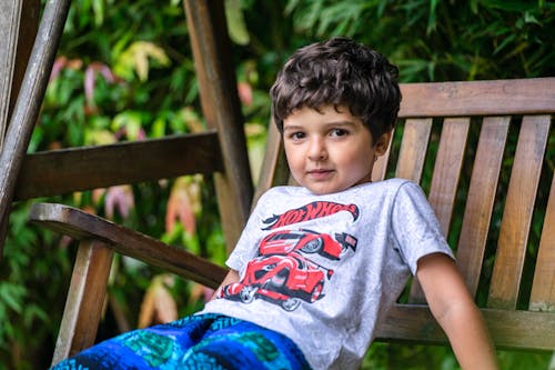 Little Boy in Gray Shirt Reclining on Wooden Bench