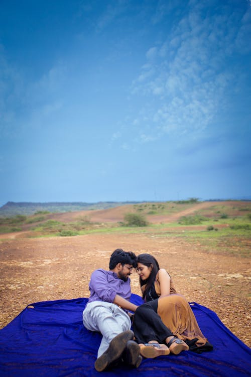 A Couple Close Together Lying on a Blanket on the Ground