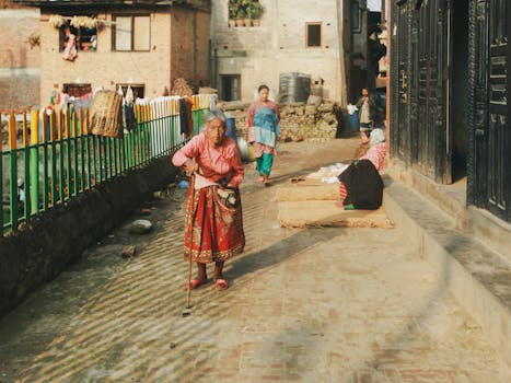 Elderly woman with walking stick strolling through lively urban street.