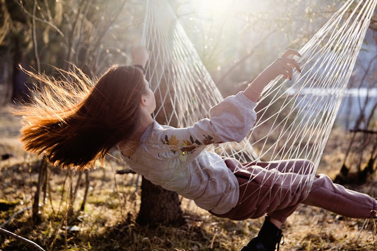 Girl With Long Red Hair Sitting In Hammock And Swinging