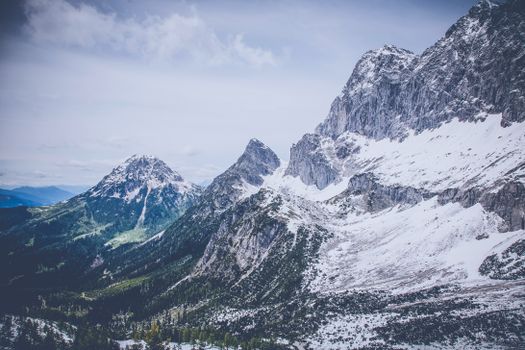 A breathtaking view of snow-covered mountains under a cloudy sky, showcasing the beauty of winter wilderness.