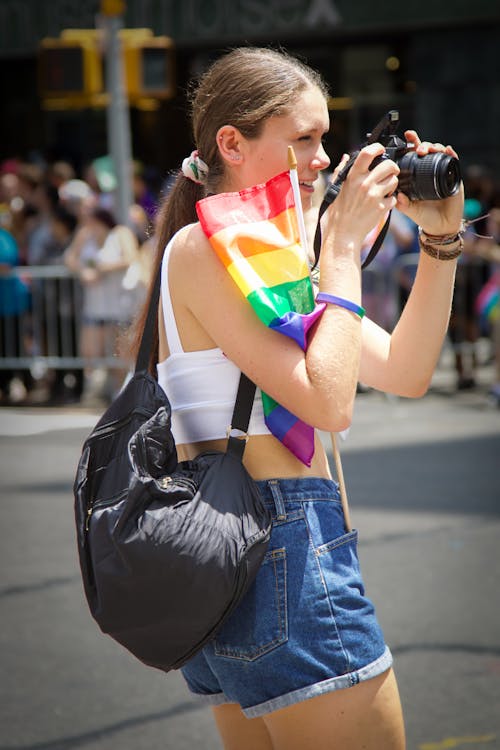 Woman with a Rainbow Flag Taking Photos with a Camera 