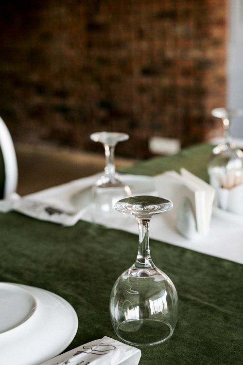 Free Upside-down wine glasses on a green tablecloth add elegance to a dinner table setting. Stock Photo