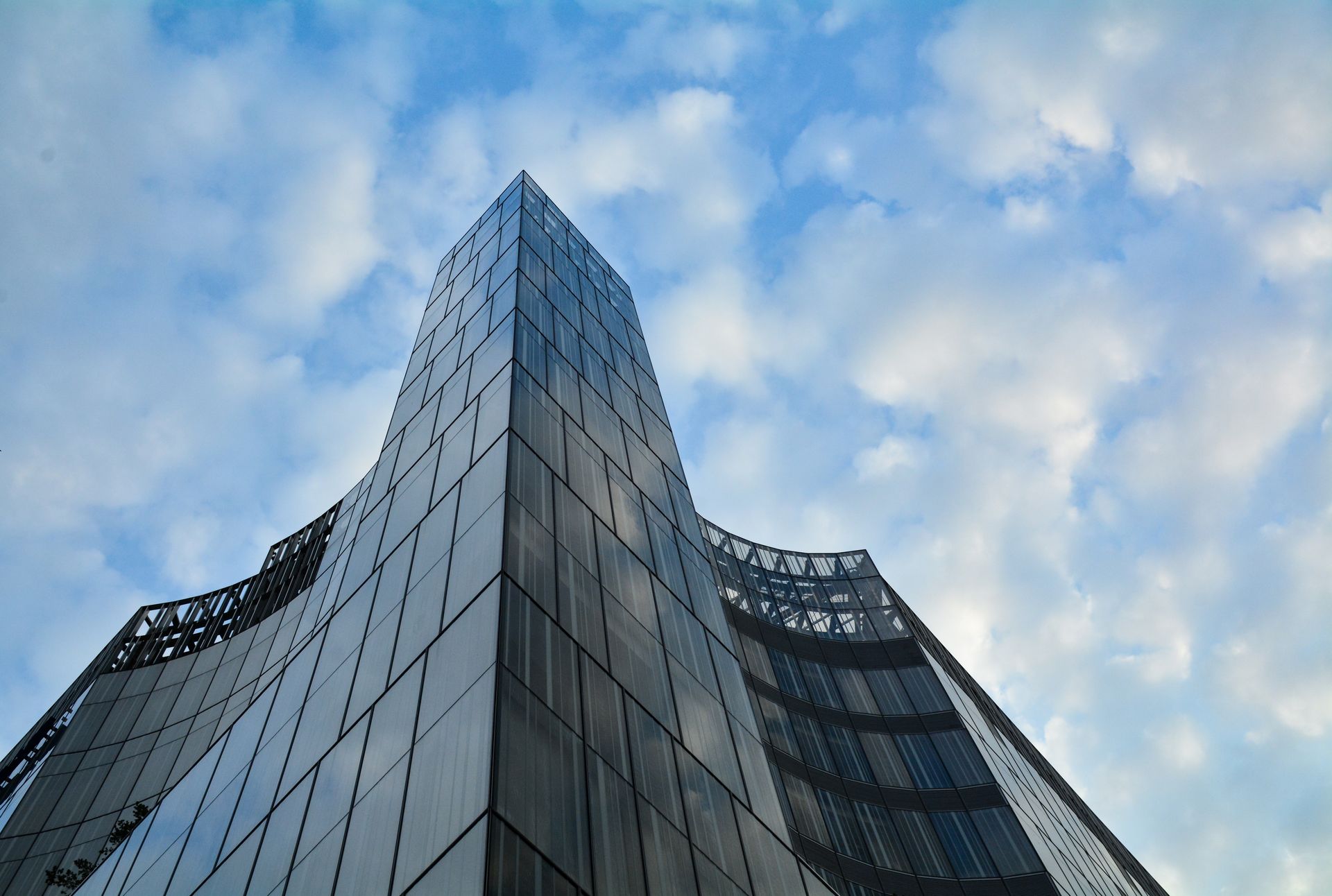 A contemporary office building with sleek glass architecture set against a vibrant sky.