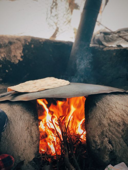 Free Traditional bread baking over an open fire, showcasing rustic cooking techniques. Stock Photo