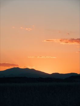 Dramatic sunset with vibrant orange sky behind mountainous silhouettes, perfect for nature backdrops.