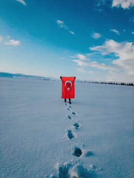 A person holding the Turkish flag stands on a snow-covered field in winter.