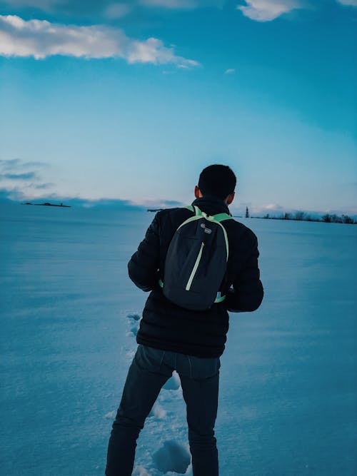 Man with a Backpack Walking on Snow