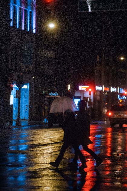 Pedestrians crossing a rainy city street at night — photo by Zeeshaan Shabbir on Pexels