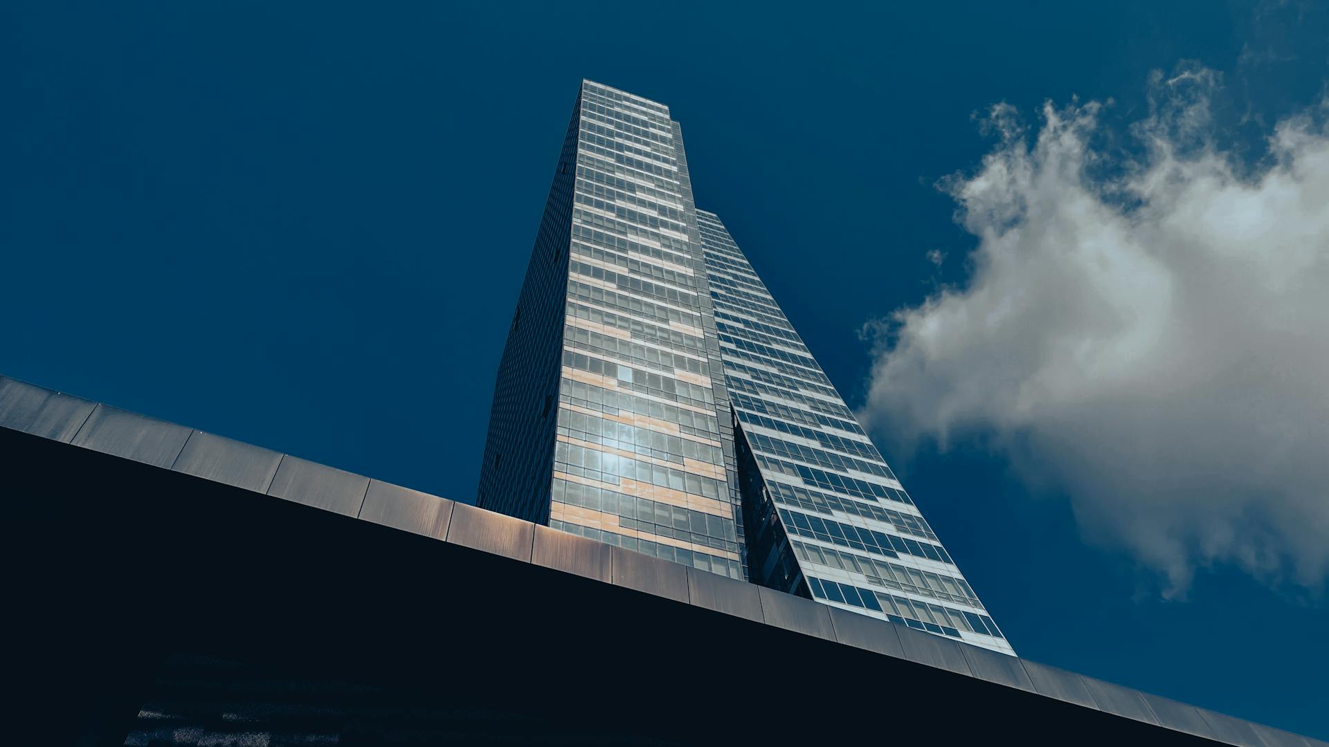 Captivating low-angle view of a towering skyscraper in Istanbul with a vibrant blue sky and clouds.