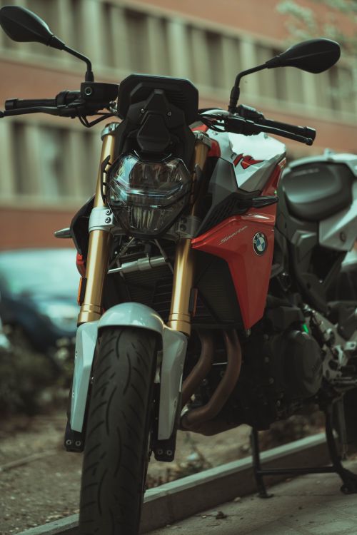 Free Close-up of a red motorcycle with a distinctive design parked on the street. Stock Photo