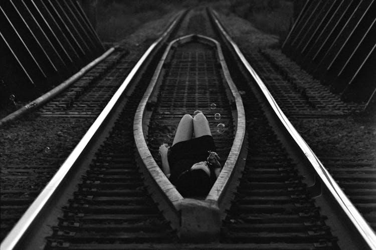 Girl Lying On Train Tracks And Blowing Soap Bubbles