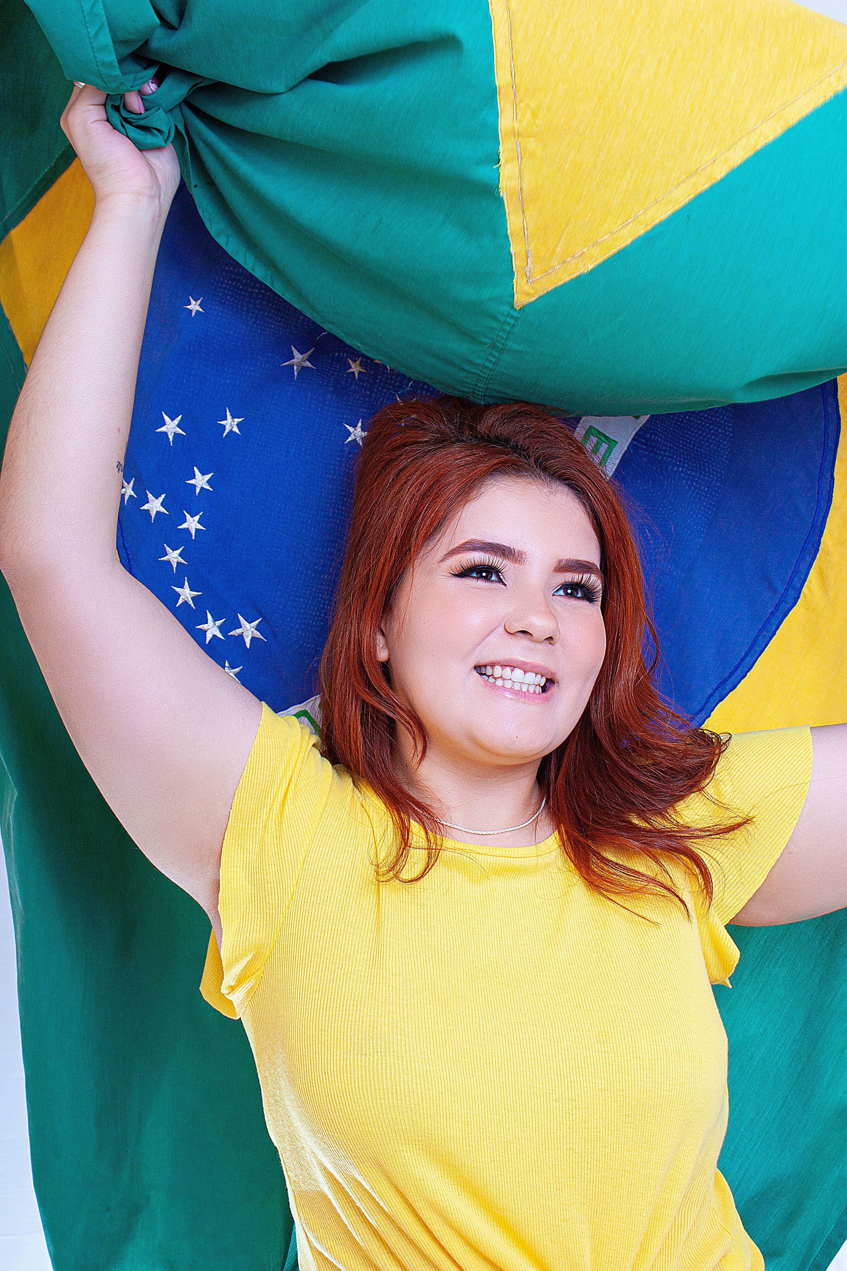 Cheerful young woman holding the Brazilian flag with joy and pride.