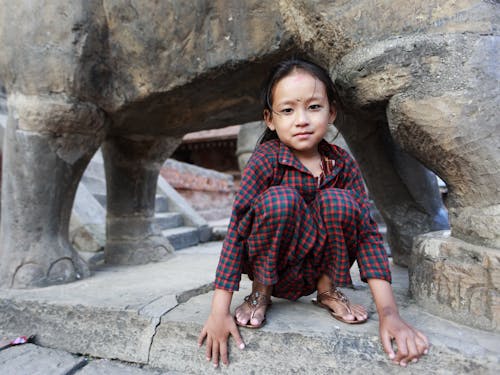 Free Child in Pajamas Sitting Under a Statue Stock Photo