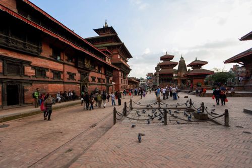 Free Vibrant scene at Durbar Square with people, pigeons, and historic architecture in Kathmandu. Stock Photo
